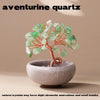 A handcrafted aventurine quartz tree with green crystals mounted on a copper wire base in a light gray bowl.