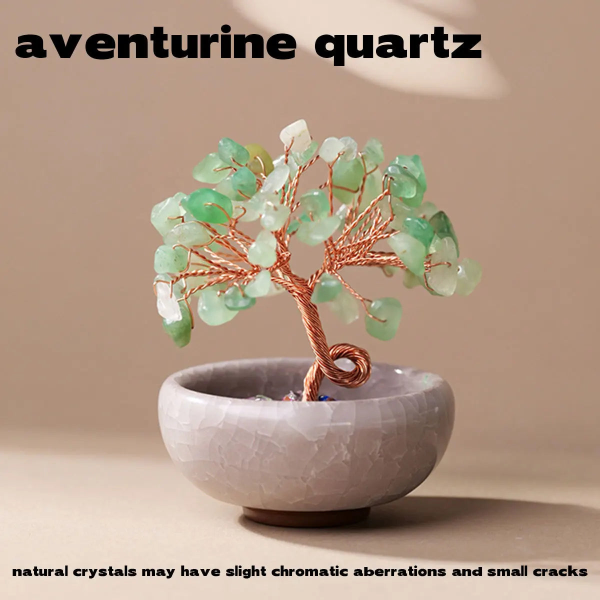 A handcrafted aventurine quartz tree with green crystals mounted on a copper wire base in a light gray bowl.