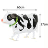 A white and black cow print foil balloon shaped like a cow with a green necklace.