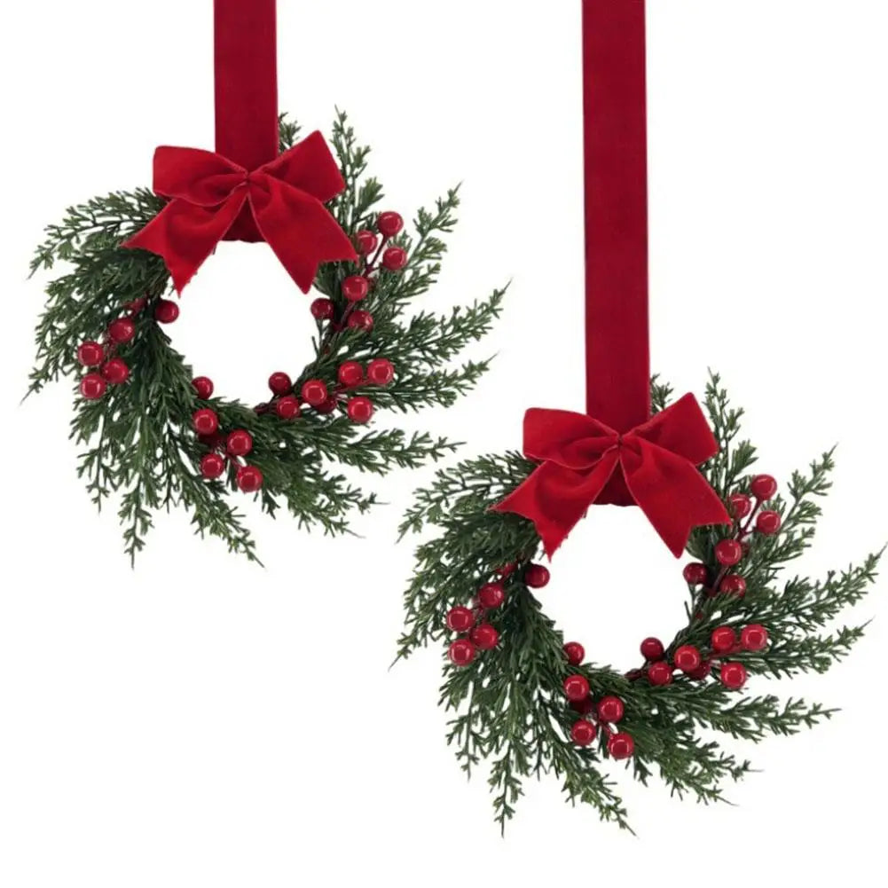 A 10-inch artificial Christmas wreath decorated with green foliage, red berries, and a red velvet bow.