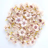 A collection of small, pale pink and cream silk artificial flower heads used for weddings, crafts, and home decor.