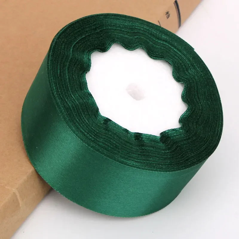 Roll of dark emerald green satin ribbon with a decorative hole for crafts and gift wrapping