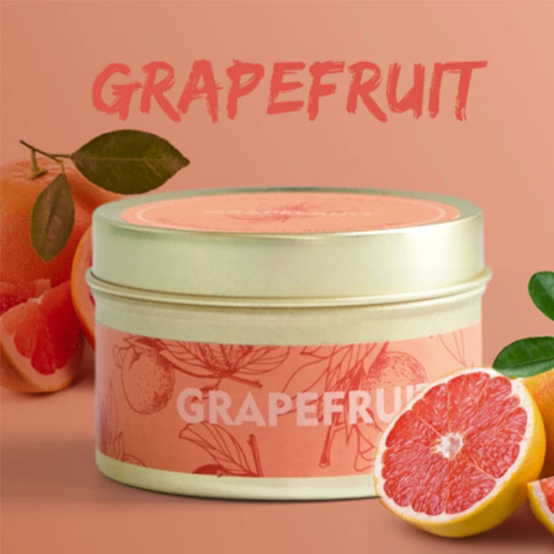 A jar of grapefruit scented soy wax travel candle with fresh grapefruit fruit nearby.