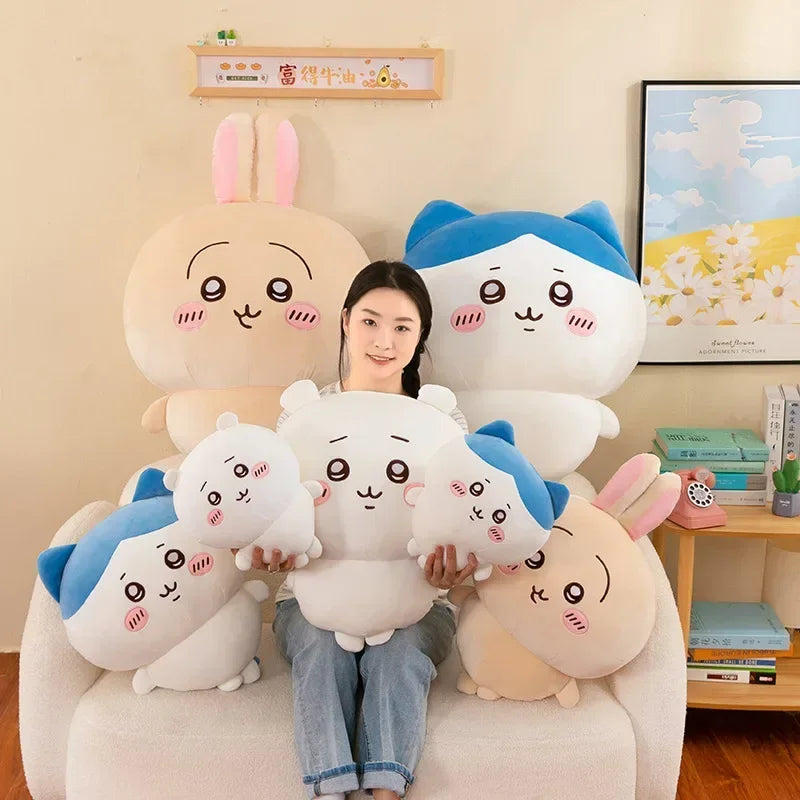 A woman is sitting on a couch surrounded by several soft, white and blue Chiikawa plush dolls.