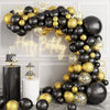 An elegant balloon garland arch featuring black and gold balloons with starburst foil accents.