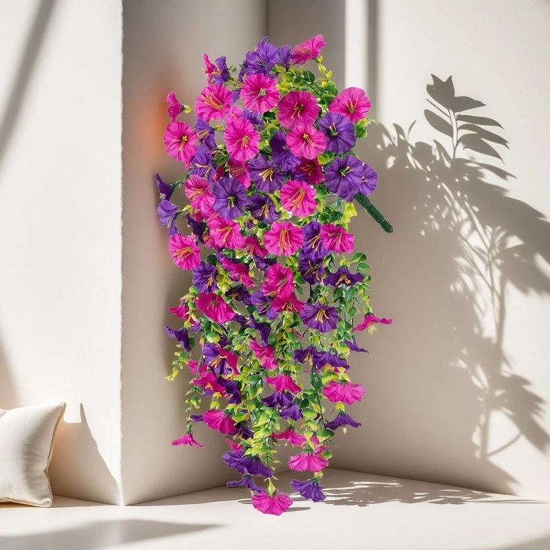 A vibrant bouquet of purple and pink artificial hanging morning glory flowers displayed against a white wall.