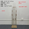 A tall gold metal candelabra set with eight slender candle holders displayed on a dark floor.
