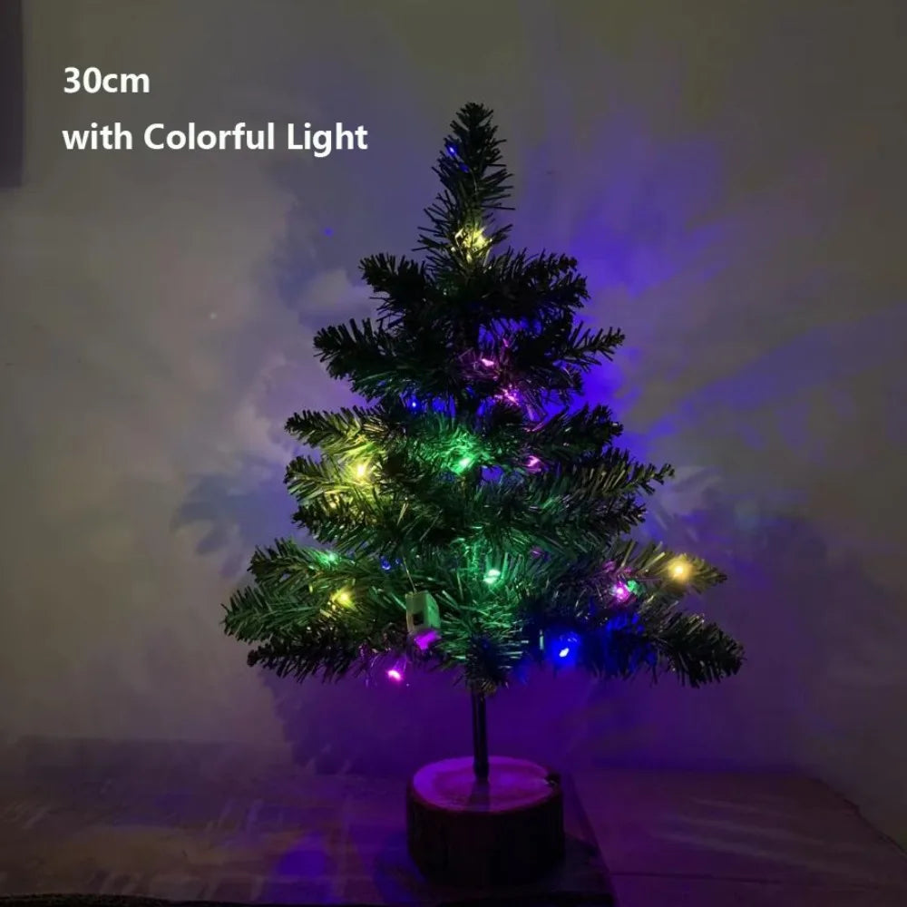 A small, decorated Christmas tree with colorful lights illuminated against a dark background.