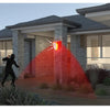 A solar-powered motion sensor alarm system with a flashing red siren illuminating a house facade.