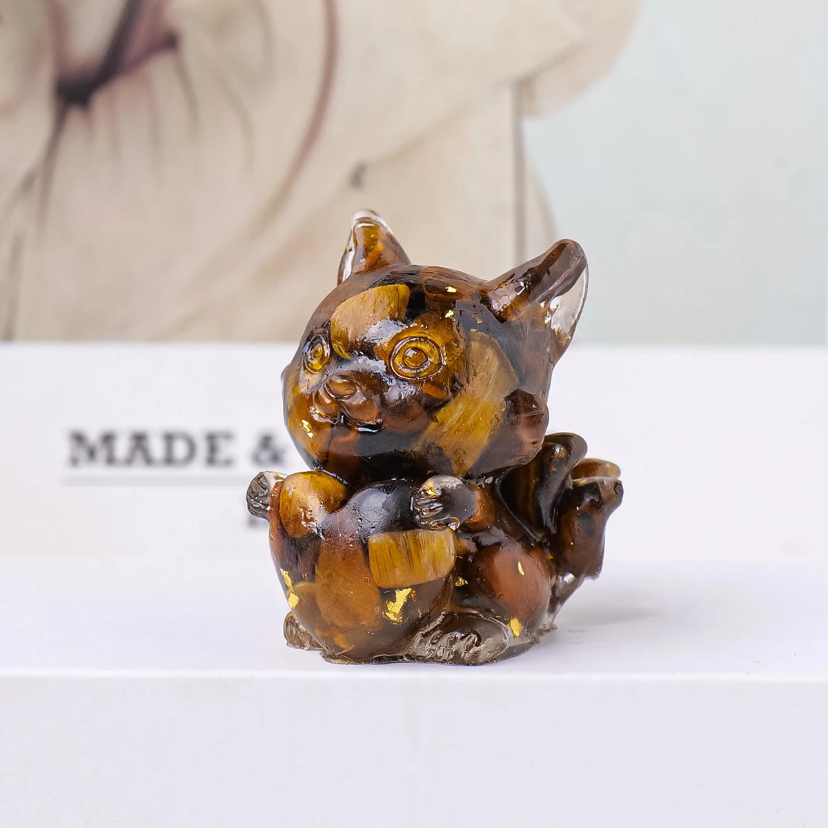 A small, amber-colored crystal sculpture of a fox resting, used for Feng Shui decor.