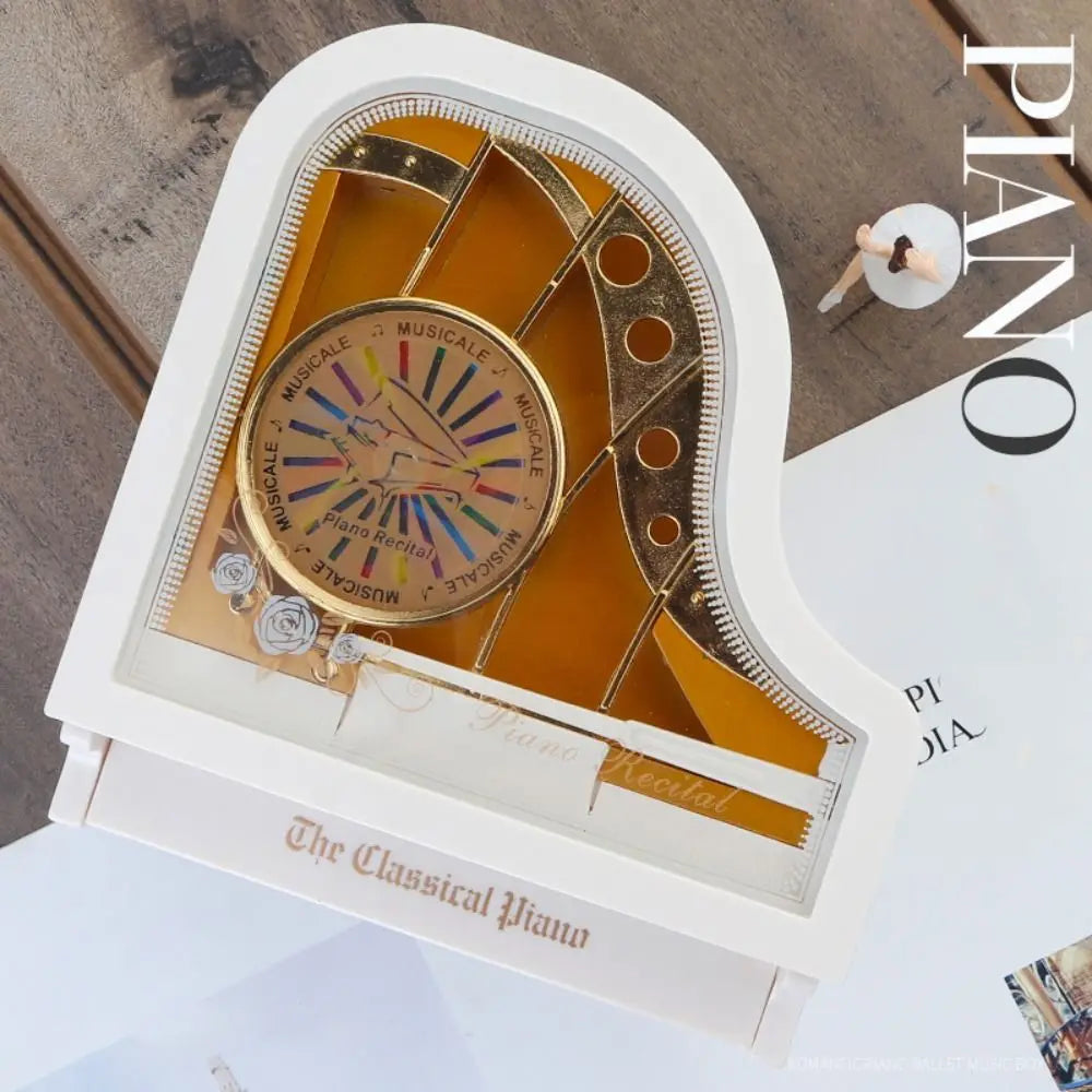 A white piano-shaped box displaying a gold musical mechanism with a spinning ballerina inside.