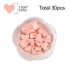 A collection of 30 pink silicone heart beads in various shapes and sizes displayed in a white dish.