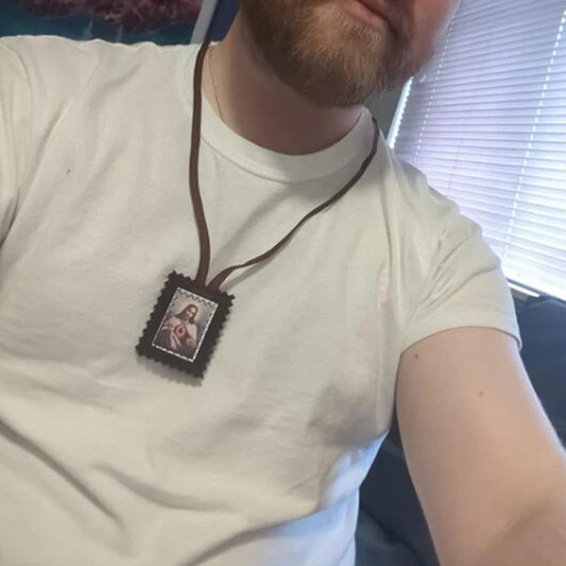 A person wearing a white t-shirt with a brown leather scapular featuring a sacred heart medal.
