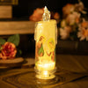 A clear glass votive candle with a flame-like LED light inside, featuring a religious scene.