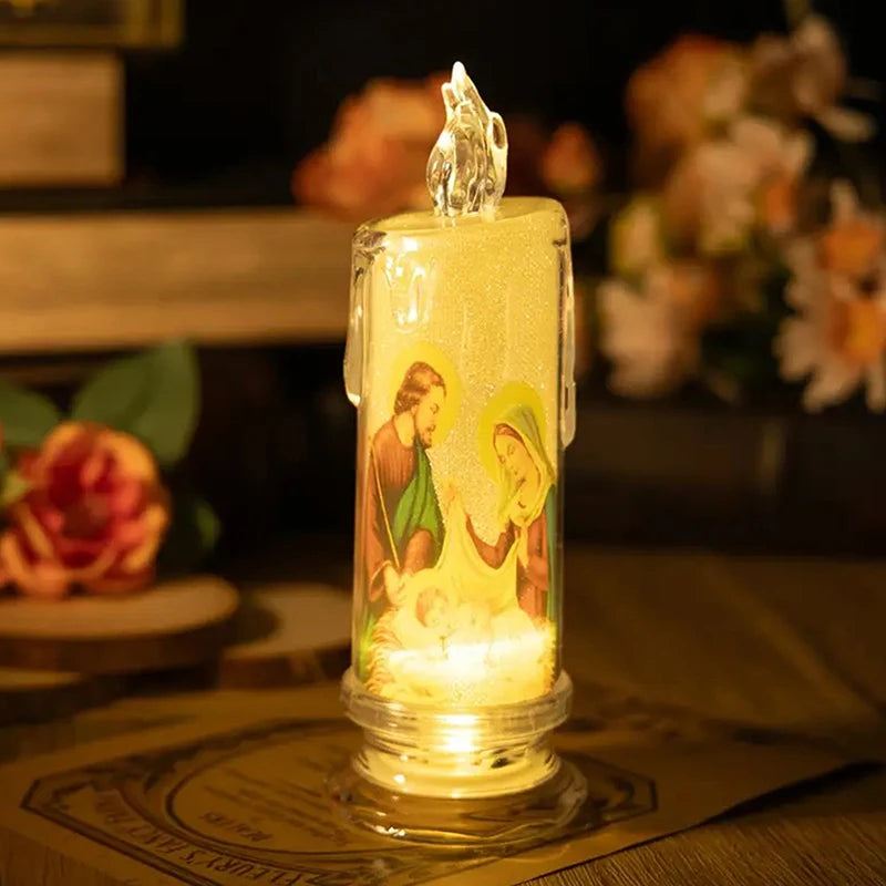 A clear glass votive candle with a flame-like LED light inside, featuring a religious scene.