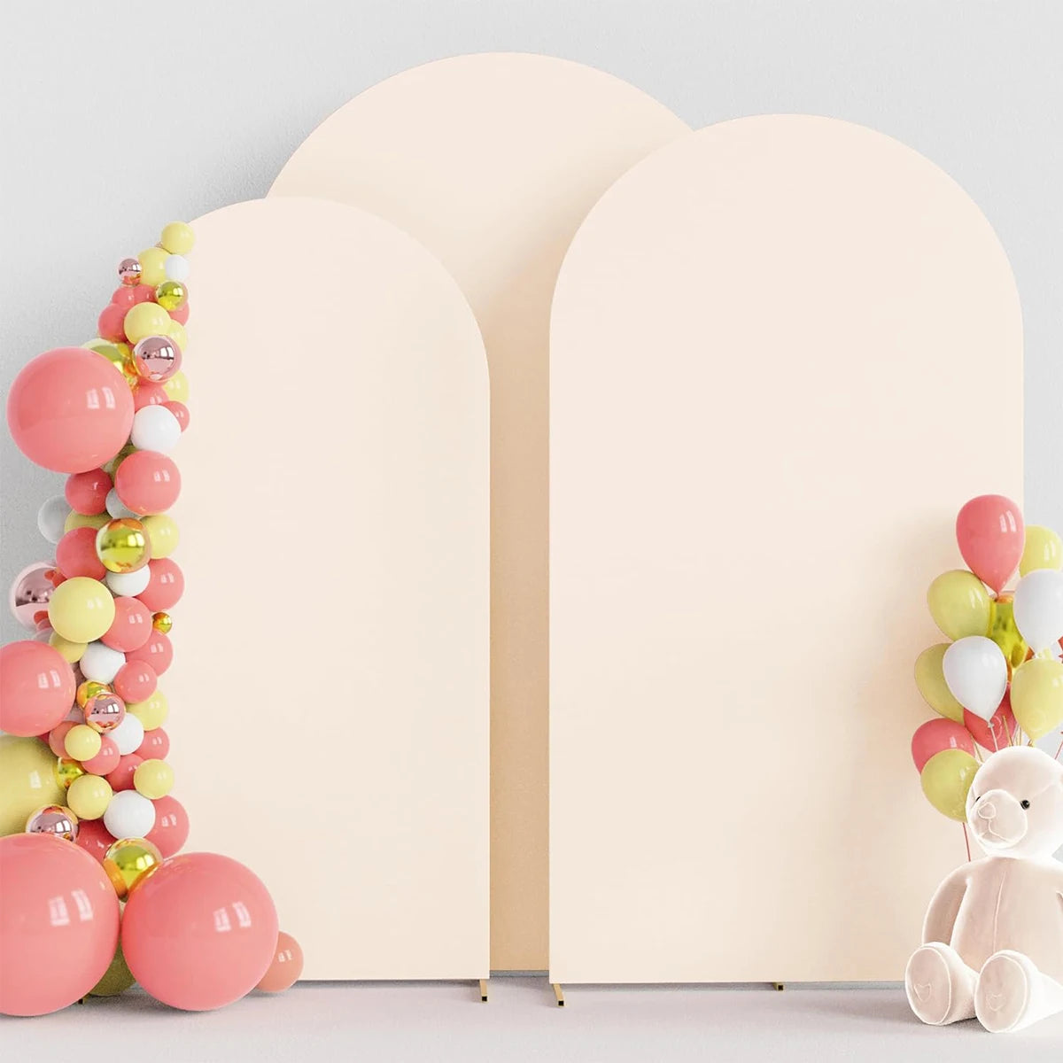 A display of pink and yellow balloons arranged in a vertical garland next to two cream-colored arch stand backdrops.
