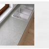 A kitchen countertop featuring a stainless steel sink set into a light marble surface.