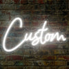 A glowing white neon sign spelling the word Custom is mounted on a textured brick wall.