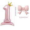 A pink foil balloon shaped like the number one with a gold crown topper and a pink bow.
