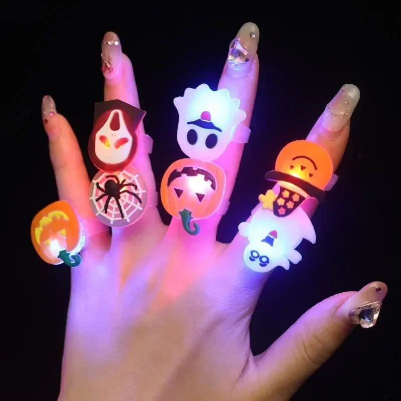 A hand wearing glow-in-the-dark Halloween rings with flashing lights on the fingers