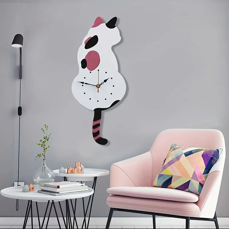 A whimsical black cat pendulum wall clock with a moving tail is displayed on a gray wall next to a pink armchair.