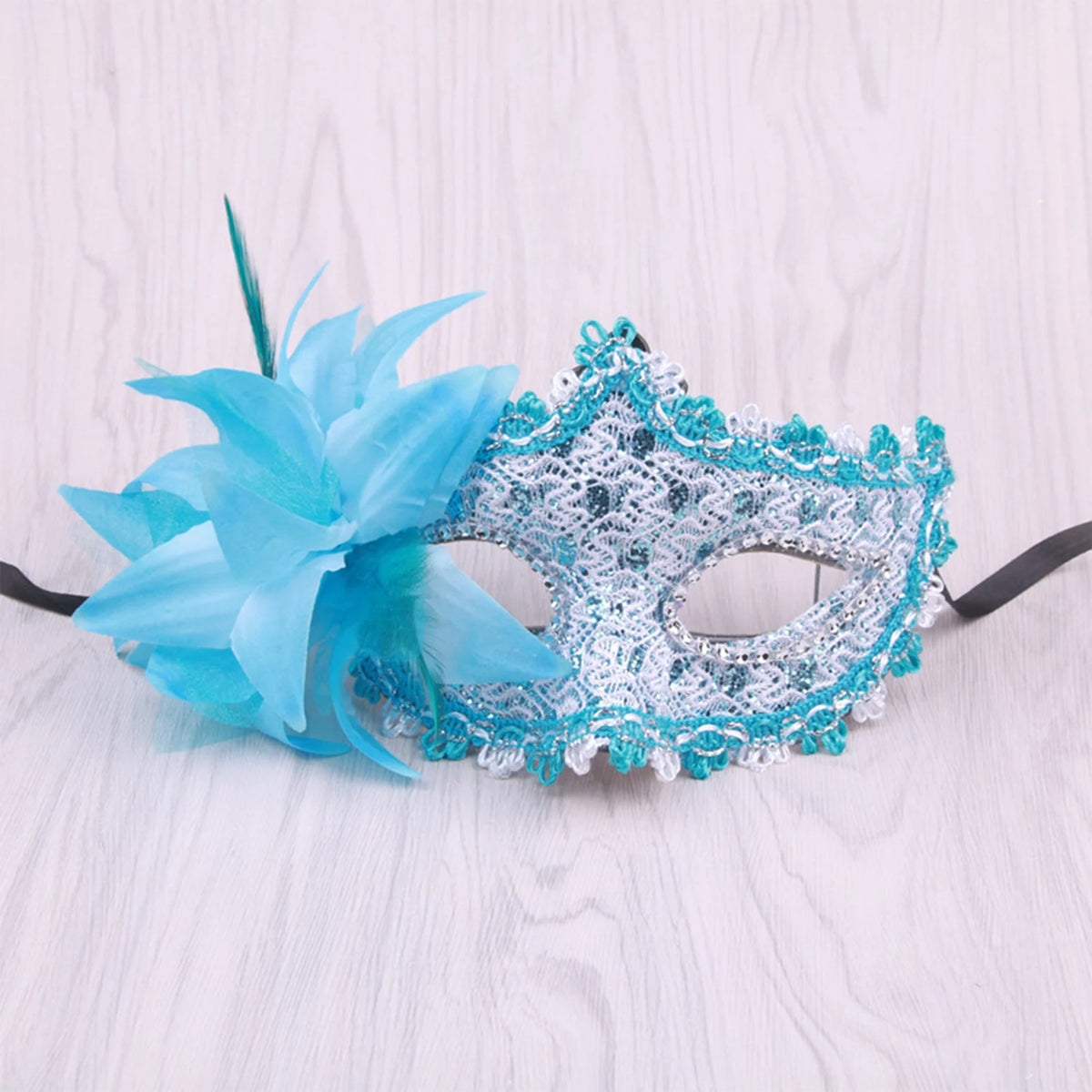 A light blue feather rhinestone masquerade mask with a blue fabric flower decoration.