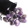 Una pila de piedras rúnicas de cristal naturales moradas y negras sobre un fondo blanco.