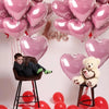 Eine Ansammlung rosa Herzballons in verschiedenen Größen und Farbtönen, darunter ein großes Herzballon und ein kleiner Teddyb
