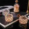A set of gold-toned crystal rings and a glass bottle filled with wooden sticks displayed on a dark surface.