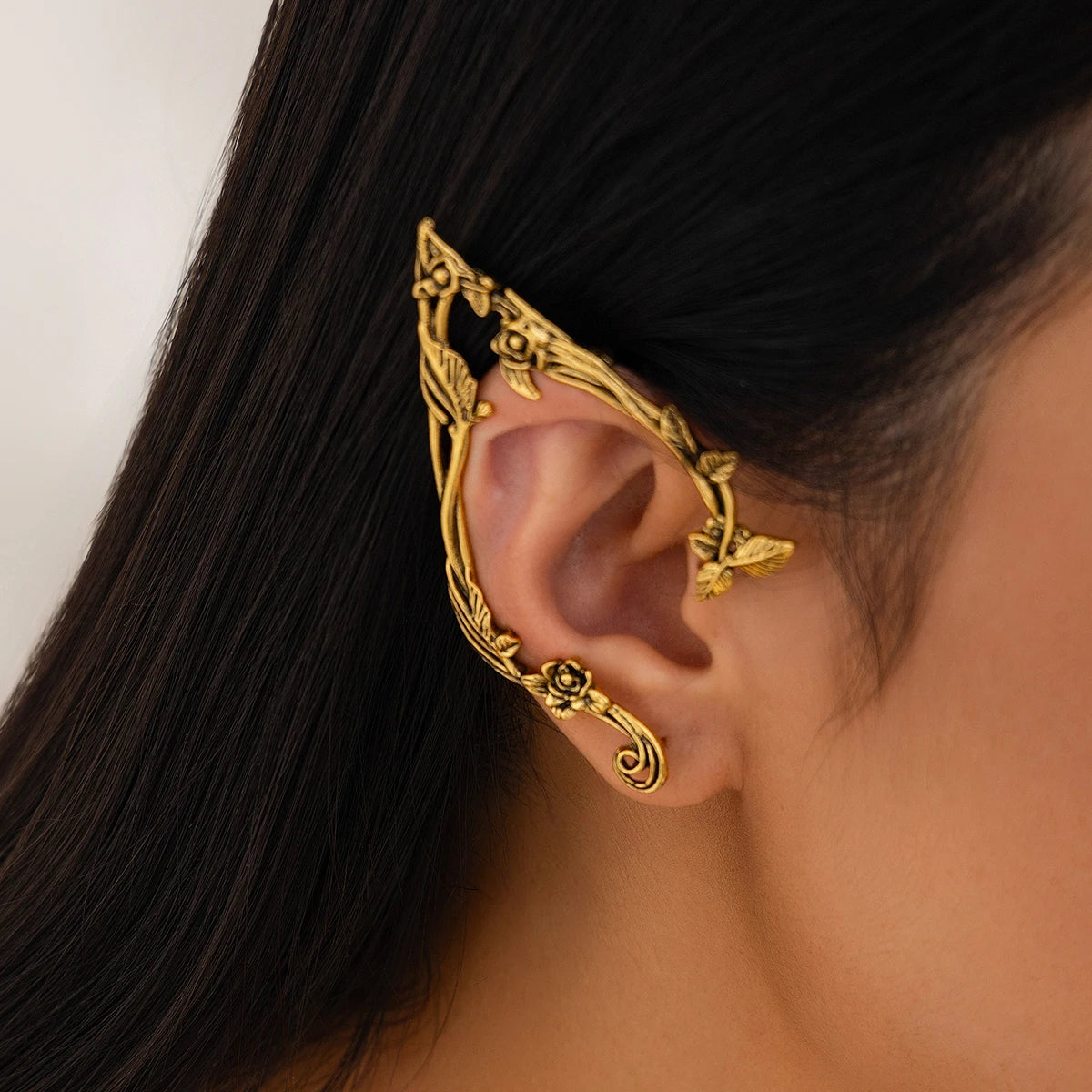Gold elf flower leaf clip earrings worn on a woman's ear.