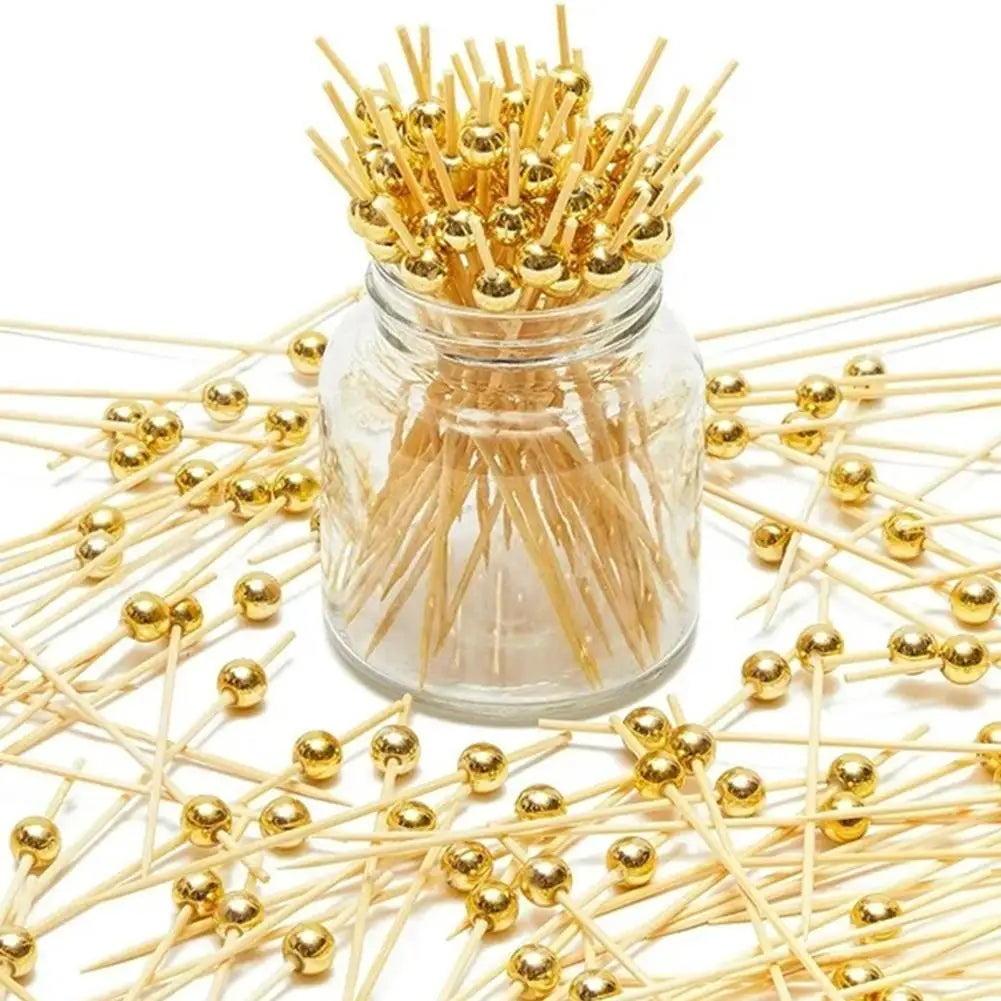 A glass jar filled with gold accent bamboo cocktail skewers for appetizers and fruit