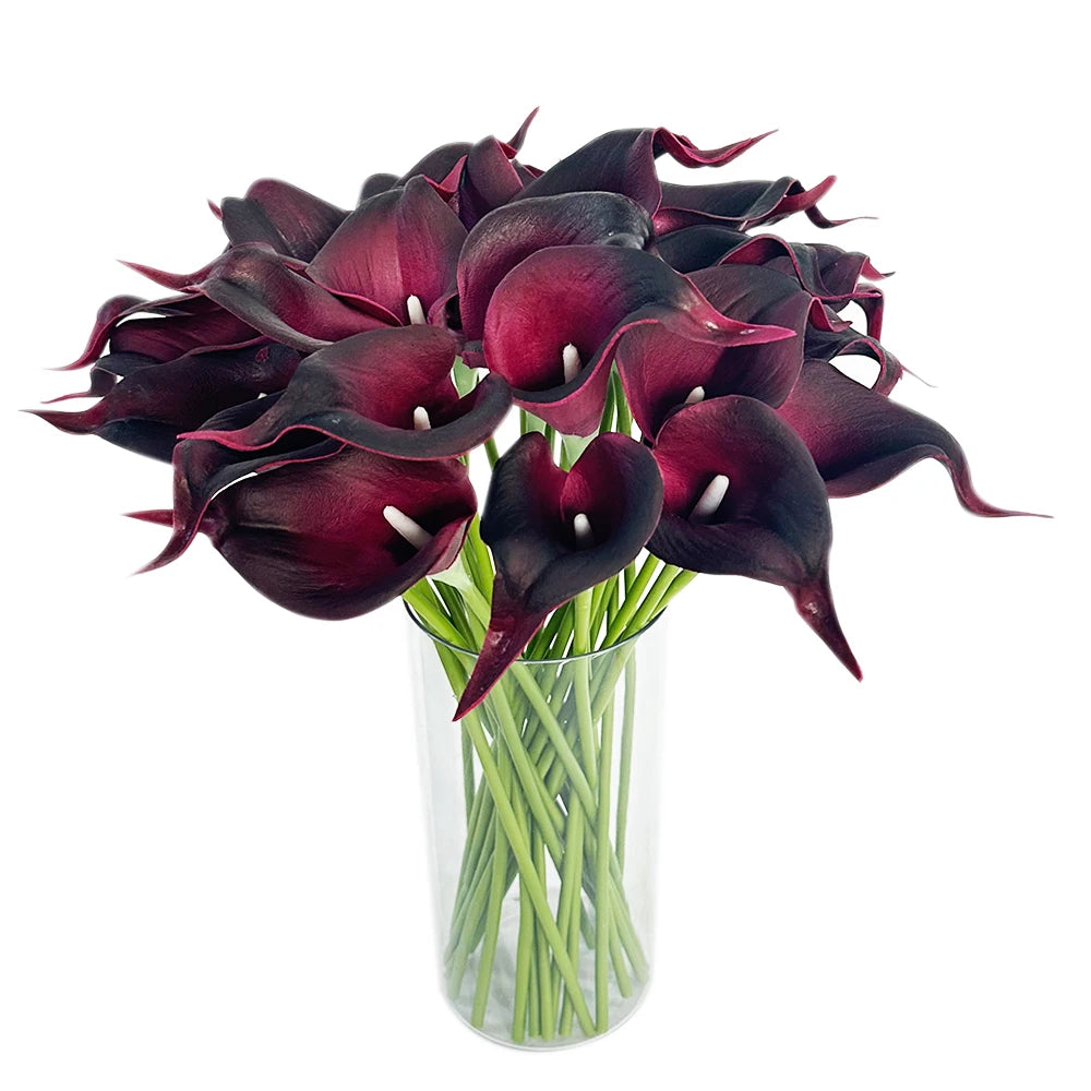A bouquet of six deep burgundy artificial calla lilies in a clear glass vase.