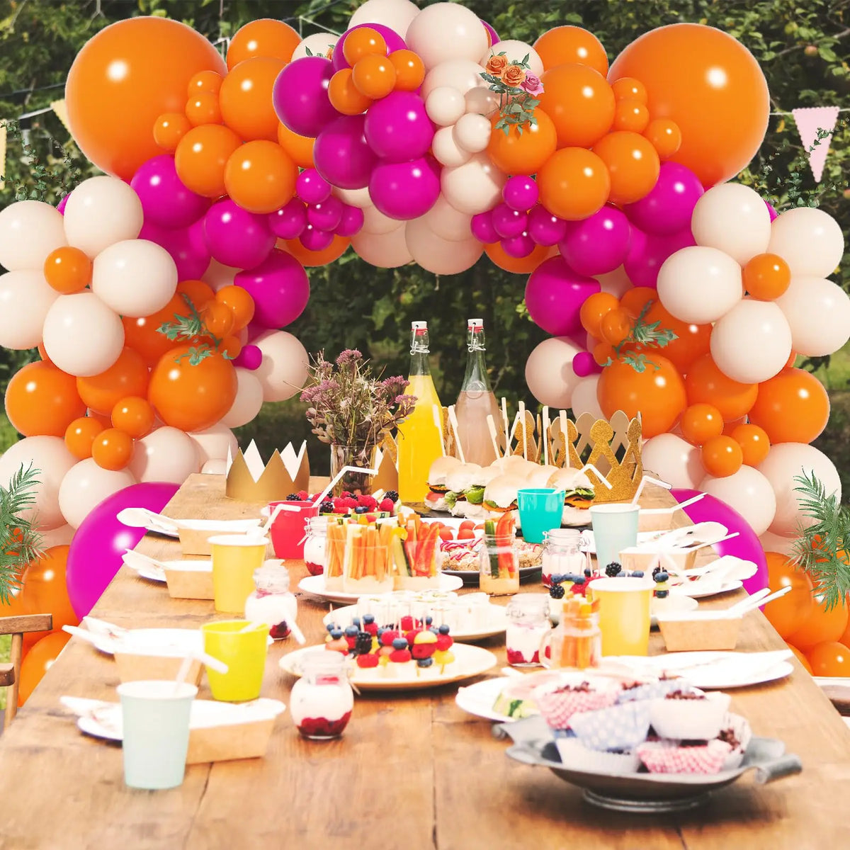 A vibrant balloon garland arch featuring pink, orange, and white balloons used for party decoration.