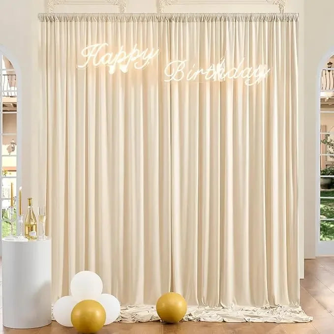 A cream-colored fabric backdrop with a happy birthday sign and gold balloons for an event