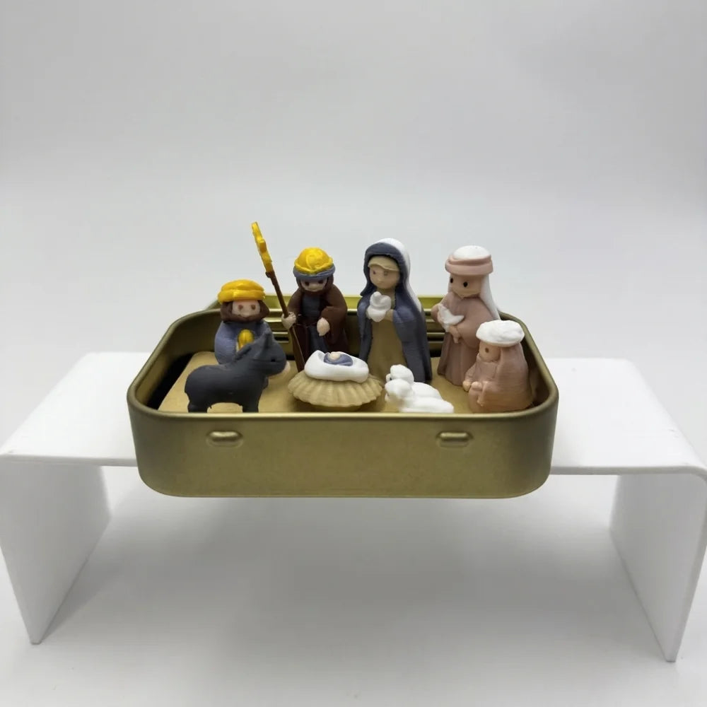 A hand-painted mini nativity set featuring figures of animals and people stored in a gold tin box.
