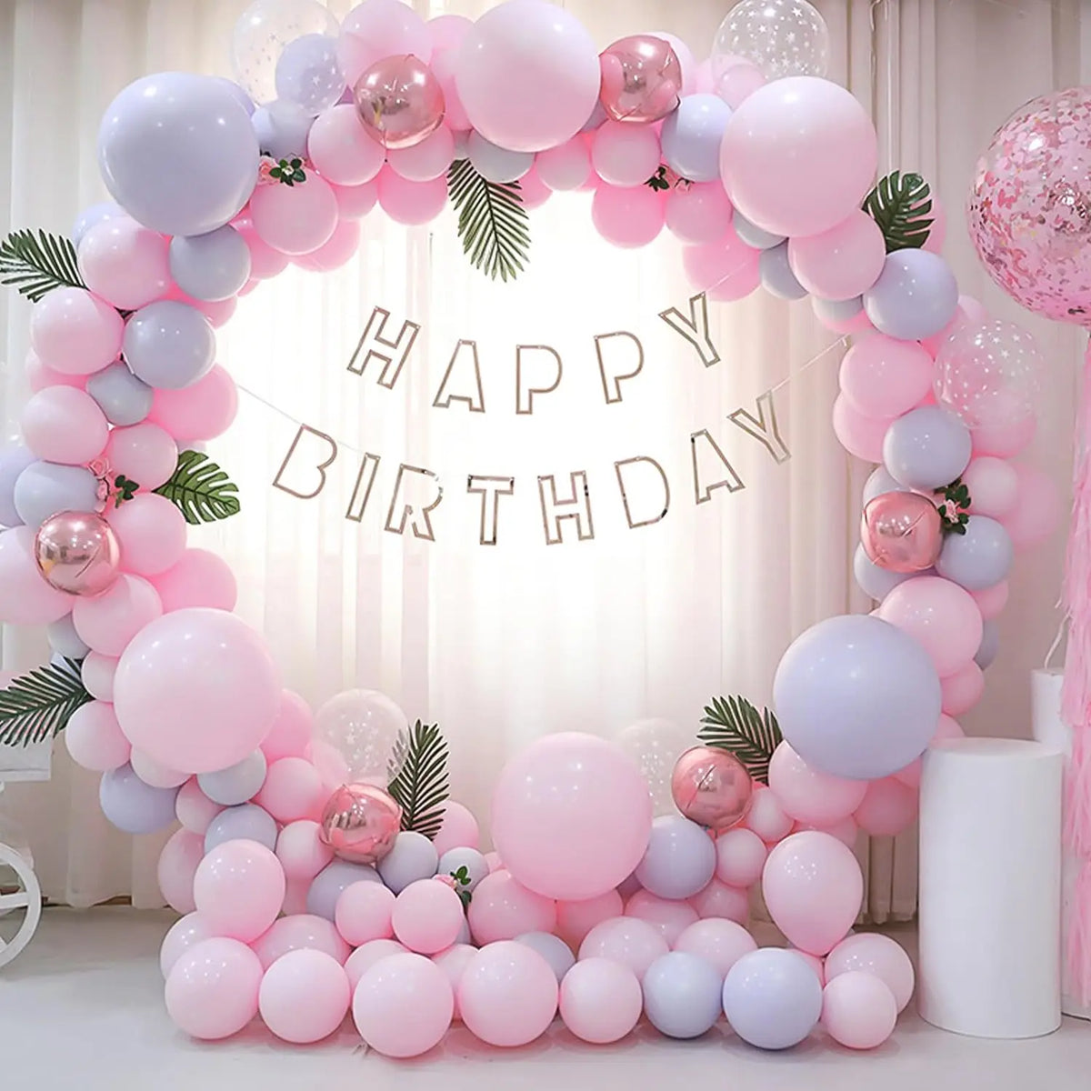 A balloon arch decoration featuring pastel pink and purple balloons for a birthday party backdrop.