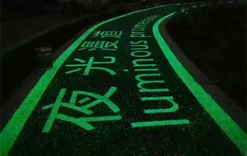 A dark path is illuminated by bright green glow-in-the-dark pebbles with Japanese and English text on the ground.
