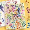 A transparent sheet of floral decal stickers featuring various watercolor-style flowers in pink, purple, orange, and blue hue
