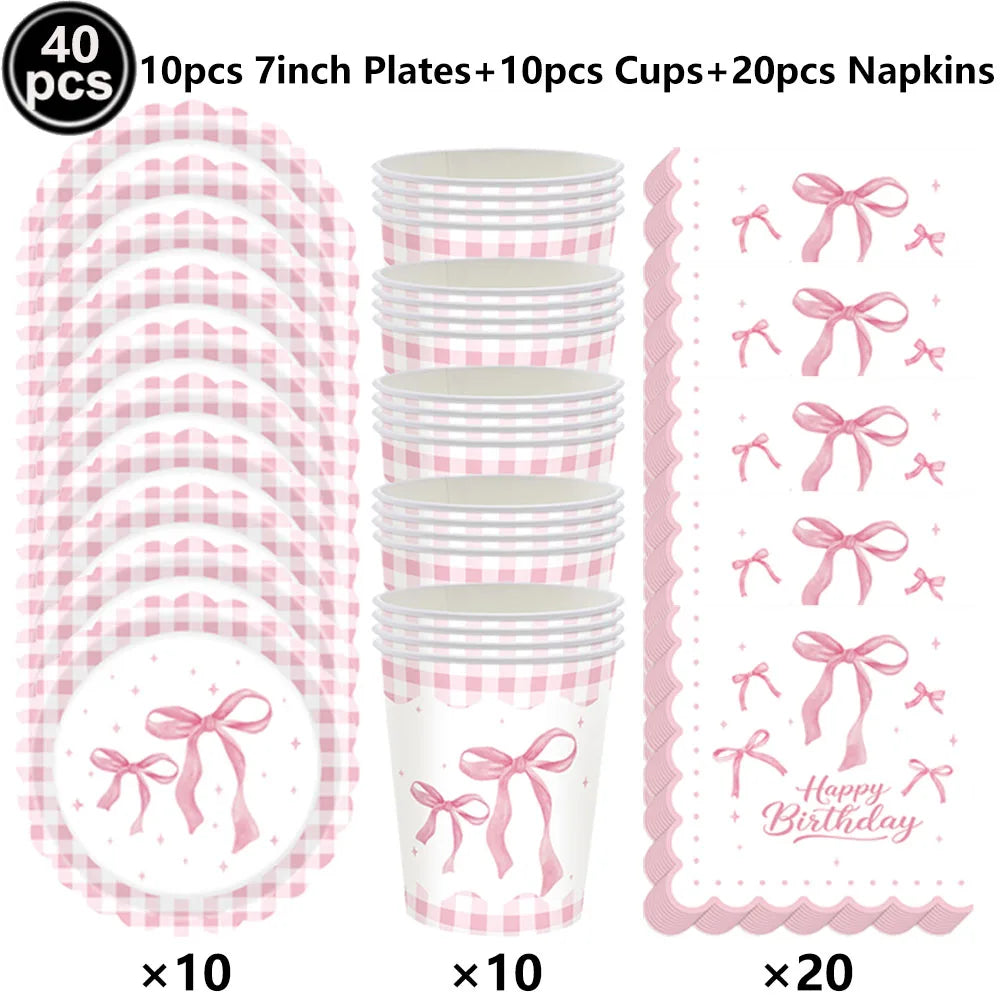 A set of pink bow themed birthday party supplies including plates cups and napkins