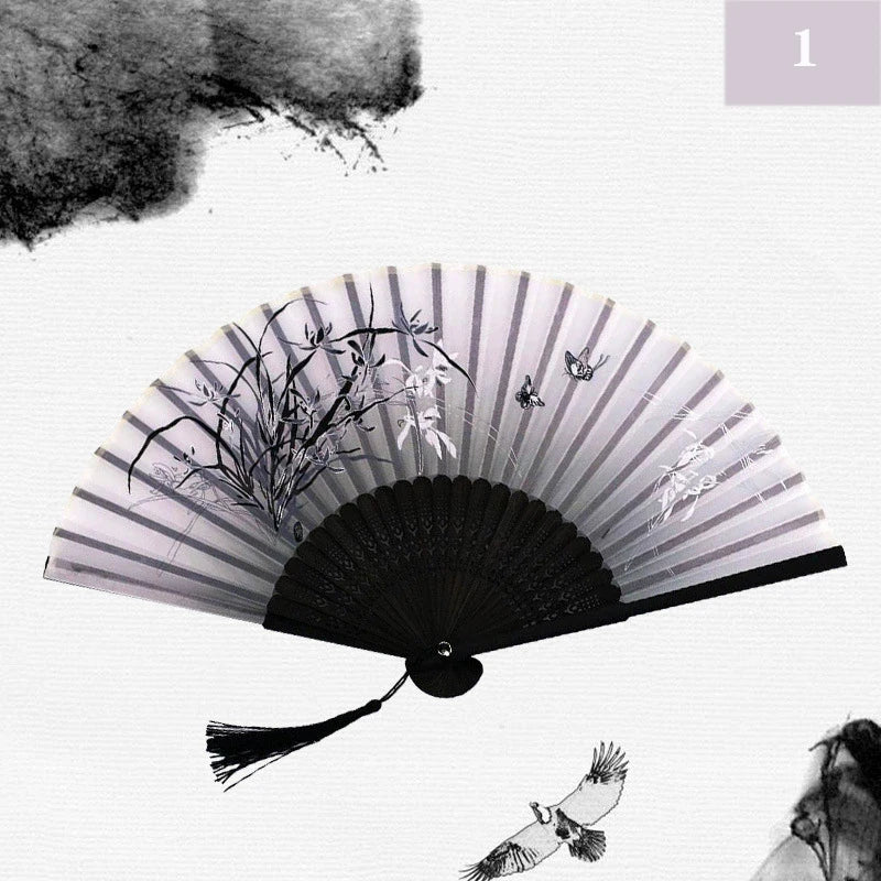 A black and white photograph of a vintage silk bamboo folding hand fan with delicate plant details.
