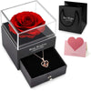 Un coffret cadeau avec une rose rouge conservée et un collier dans une boîte noire avec une carte rose.