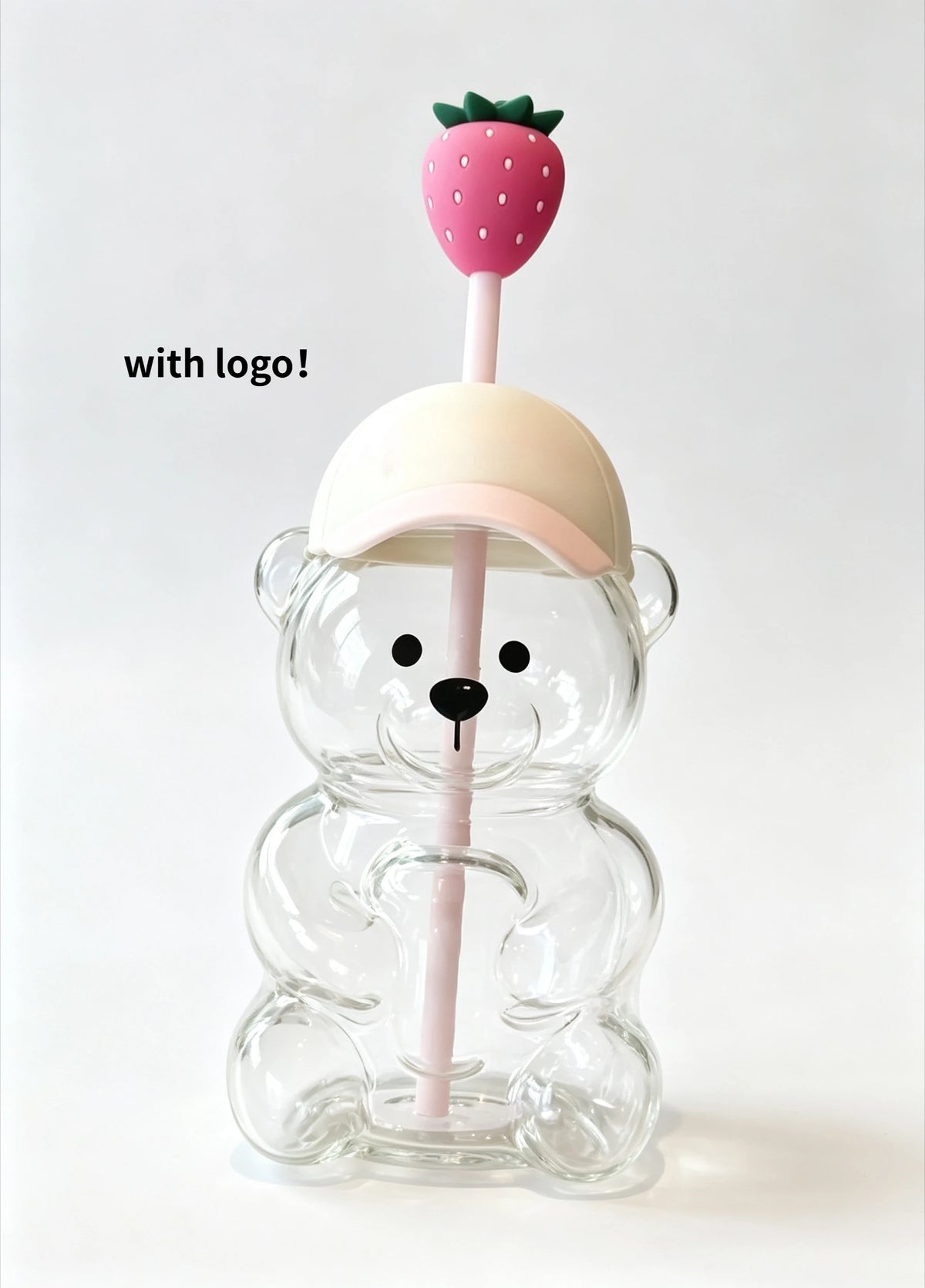 A clear glass coffee cup with a pink strawberry on a stick is held by a bear-shaped clear glass holder.