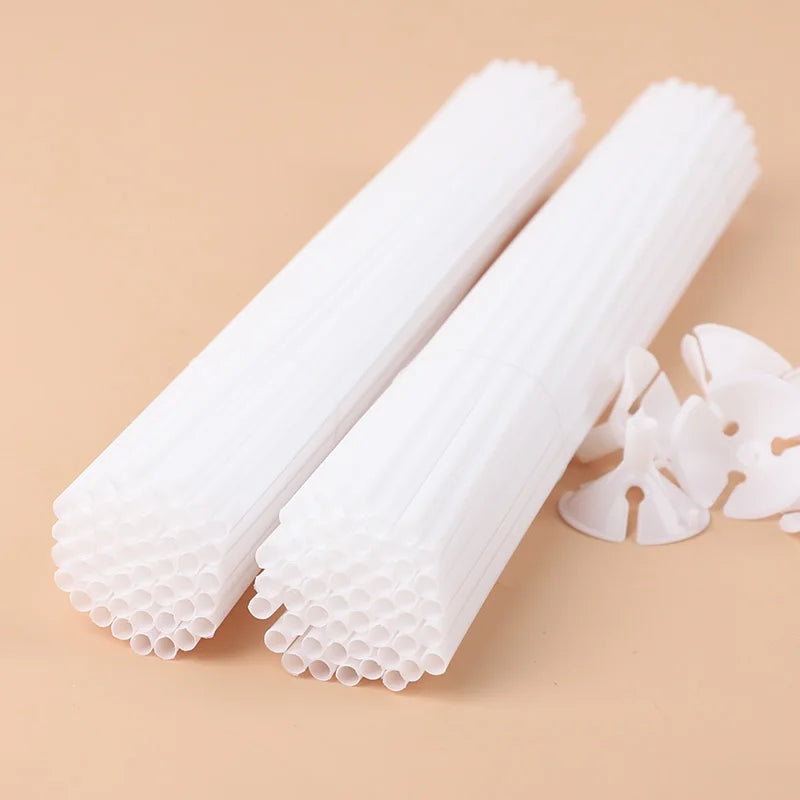 White macaron balloon sticks with holder cups for party decor shown diagonally on a beige surface