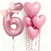 Pink foil balloons shaped like the number 6 and hearts with bows for party decoration