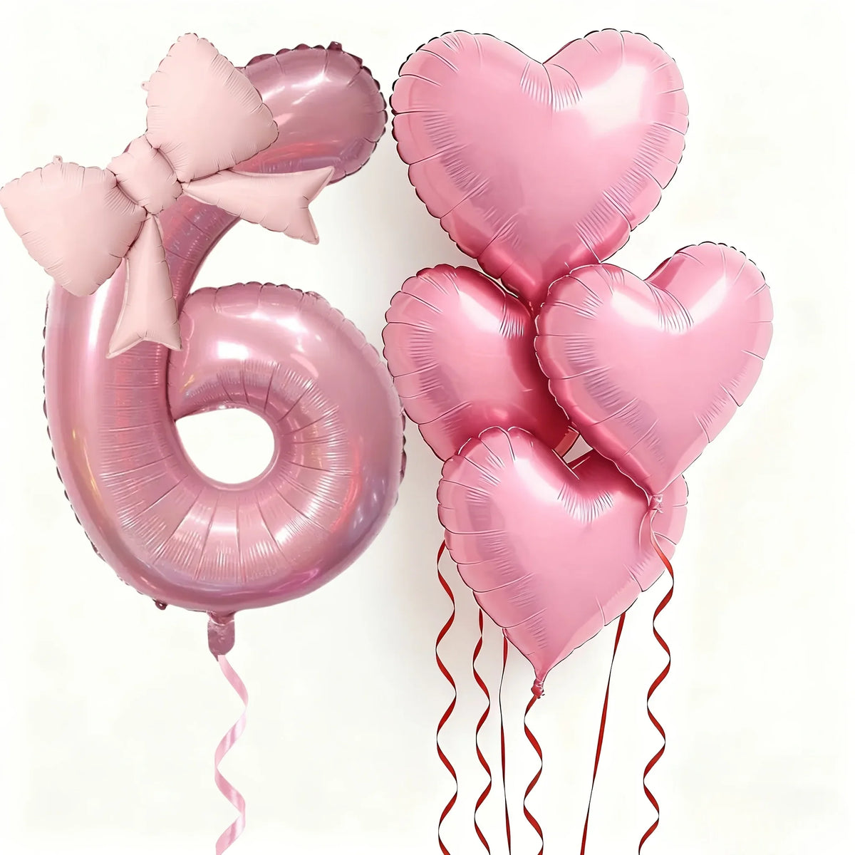 Pink foil balloons shaped like the number 6 and hearts with bows for party decoration