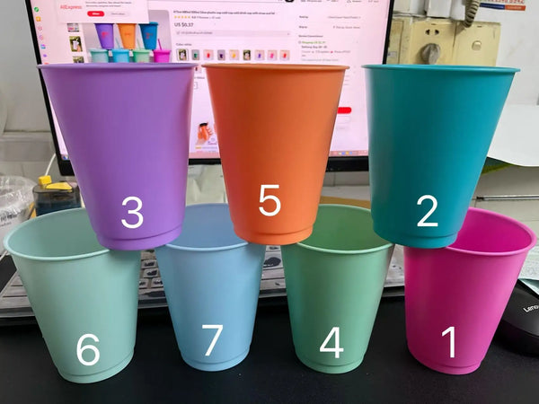 Seven plastic cold cups in various colors including purple, orange, teal, and pink, displayed on a black surface.