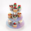 A three-tier rainbow cupcake stand displaying various decorated cupcakes with colorful frosting and toppings.
