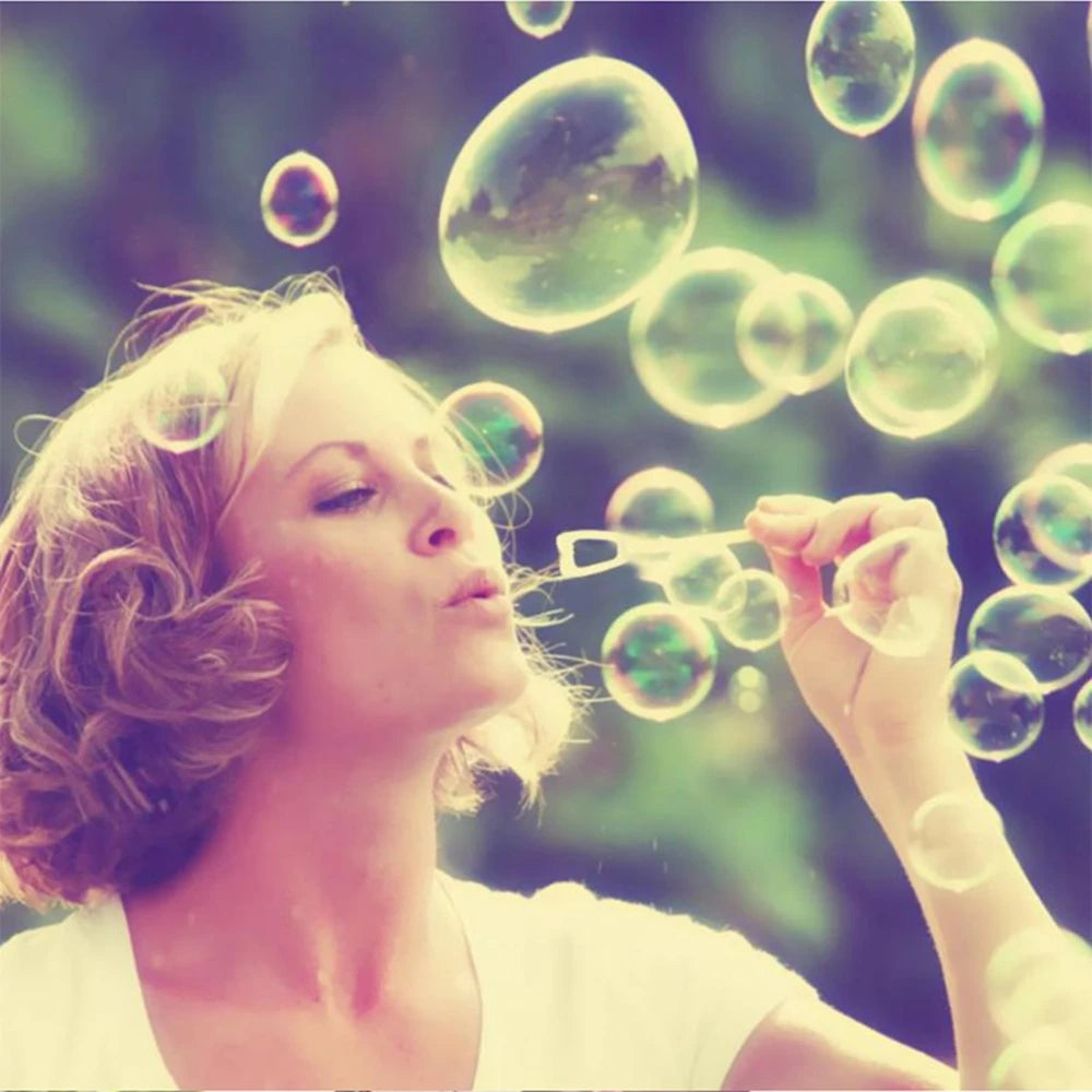 A woman is blowing bubbles with her fingers, creating numerous iridescent soap bubbles in the air.