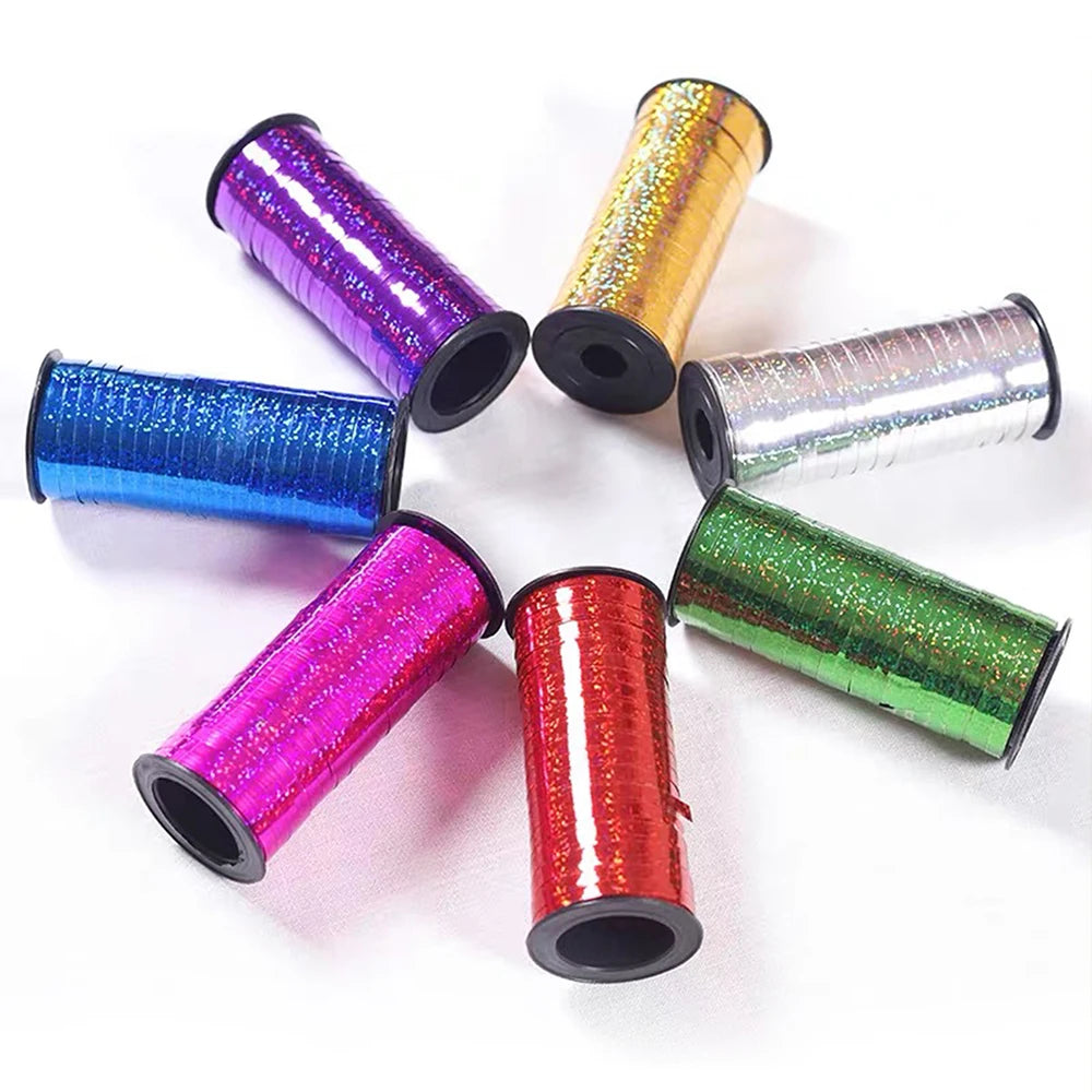 A collection of colorful glitter curling ribbon rolls in various shades including purple, gold, blue, silver, and green.