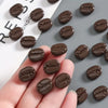 Une main tient un ensemble de huit aimants à réfrigérateur réalistes en grains de café brun foncé sur un fond gris.